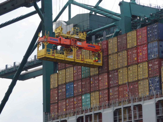 Workers on a crane trolley preparing to unload containers