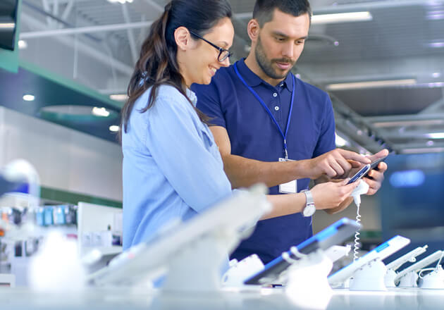 Employee at an electronics store showing a device to a female customer