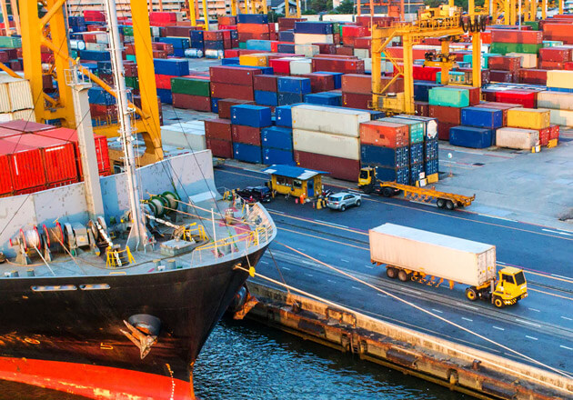 Docked cargo ship with containers in the background and trucking driving away