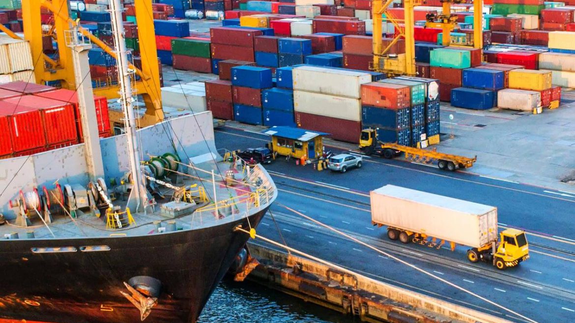 Docked cargo ship with containers in the background and trucking driving away