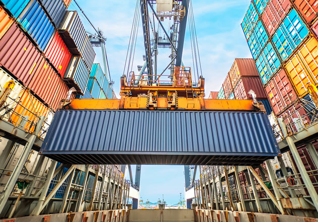 Dock crane moving a container with containers stacked on both sides