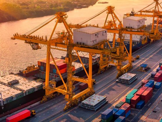 Aerial view of a sun rise over a working dock of cranes and containers stacked