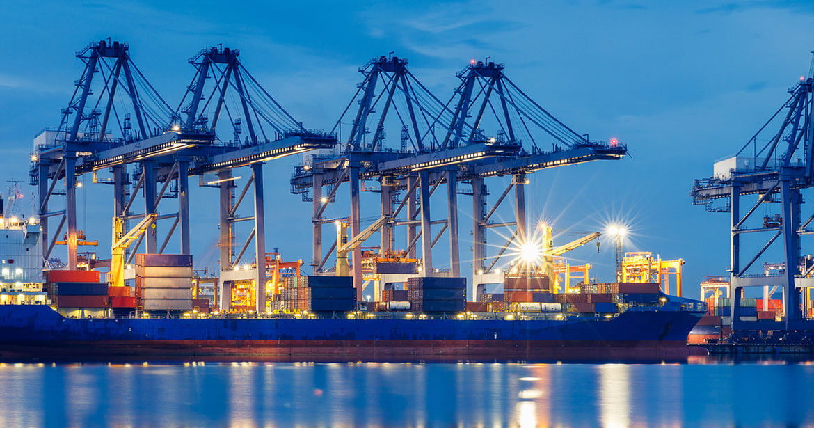 Docked container ship at dusk with dock cranes in the background