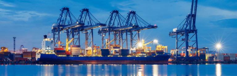 Docked container ship at dusk with dock cranes in the background