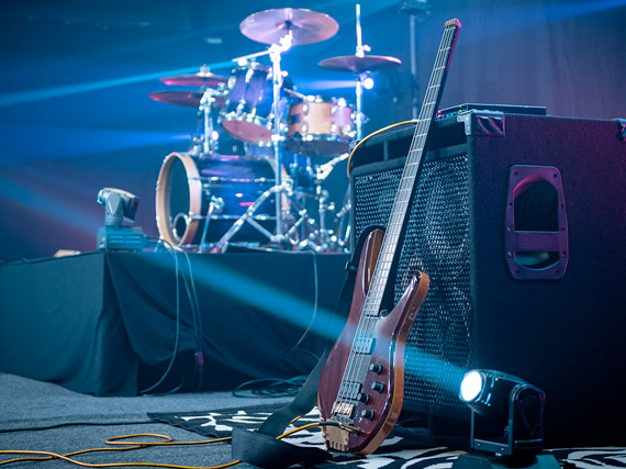 Guitar propped against a speaker with drum kit in background