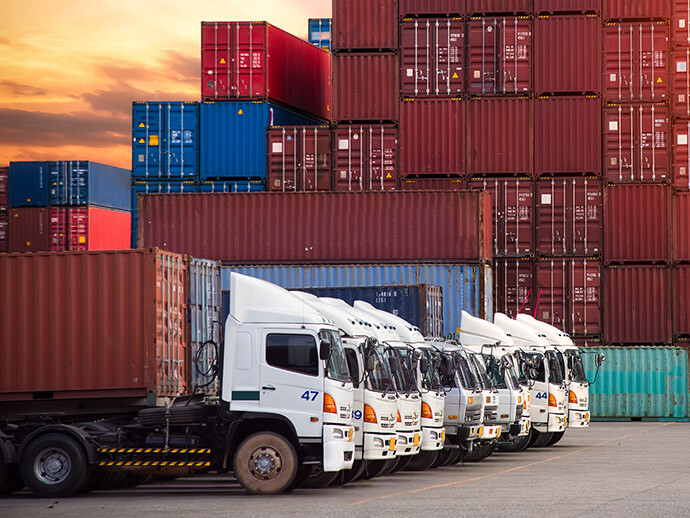 Row of trucks against a background of stacked containers